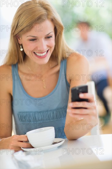 Mid adult woman drinking coffee and texting.