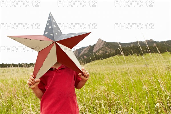 Boy (6-7) playing with star with American flag pattern. Photo : Shawn O'Connor