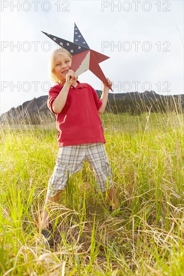 Boy (6-7) playing with star with American flag pattern. Photo : Shawn O'Connor