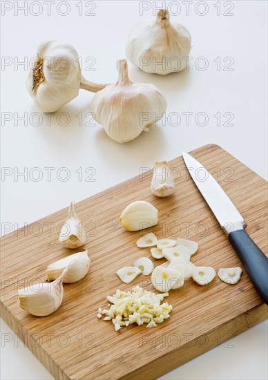 Studio shot of fresh garlic being chopped on cutting board.