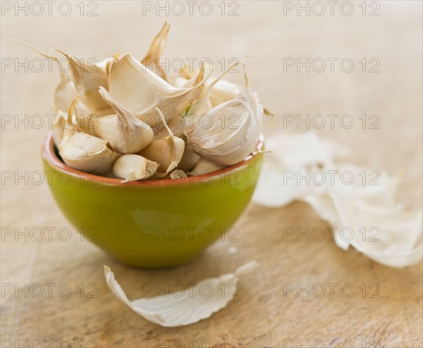 Studio shot of fresh garlic cloves in green bowl.