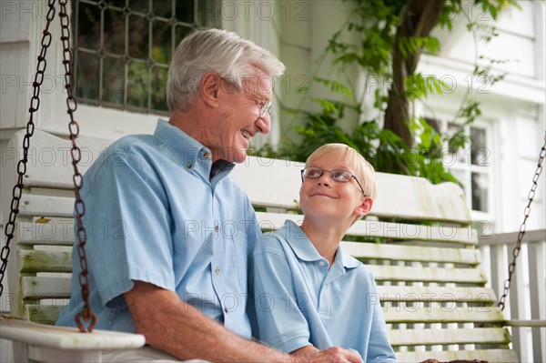 Grandfather and grandson (10-11) sitting on porch swing.