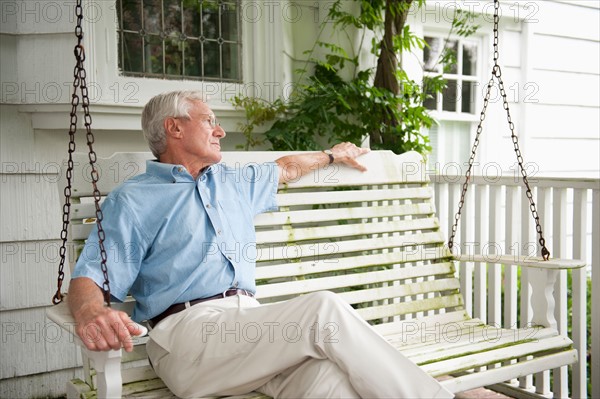 Senior man sitting on porch swing.