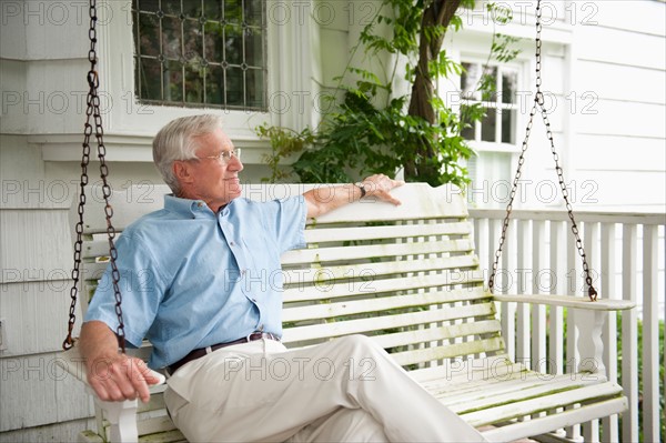 Senior man sitting on porch swing.