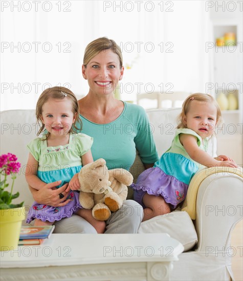 Portrait of mother with daughters (2-3) on sofa.