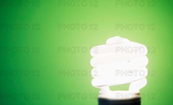 Studio shot of energy efficient lightbulb on green background.