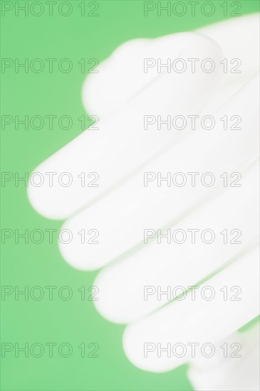 Studio shot of energy efficient lightbulb on green background.