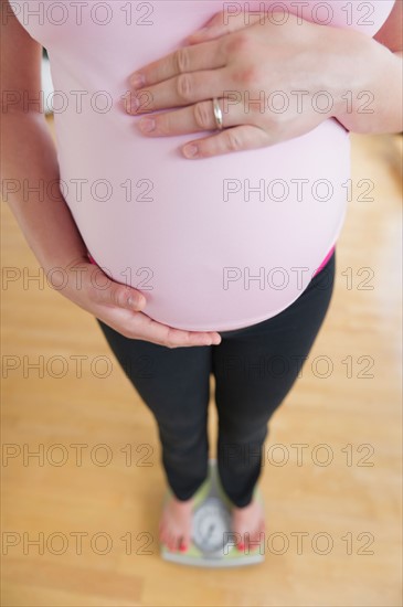 Pregnant woman weighing herself.