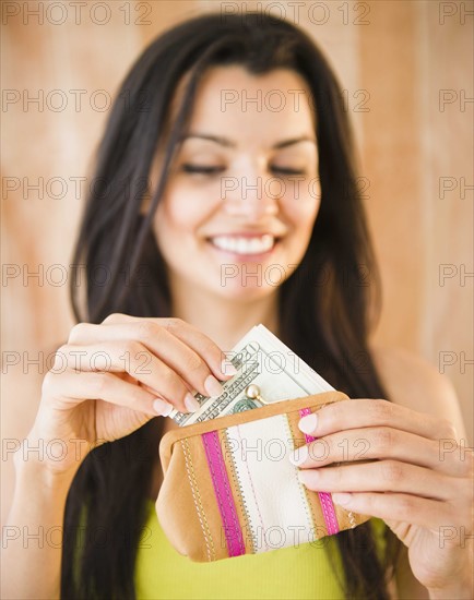 Portrait of smiling woman taking money from purse. Photo : Jamie Grill