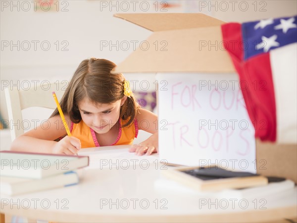 Girl ( 6-7) working at desk for charity. Photo : Jamie Grill