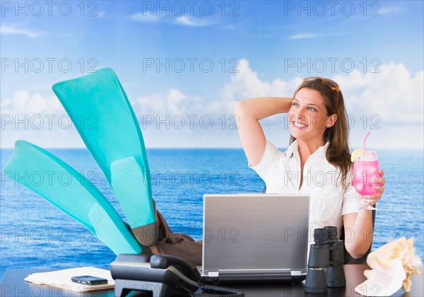 Woman in flippers daydreaming at desk. Photo : Daniel Grill