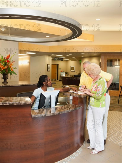 Senior people at reception desk in hospital.