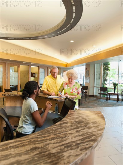 Senior people at reception desk in hospital.