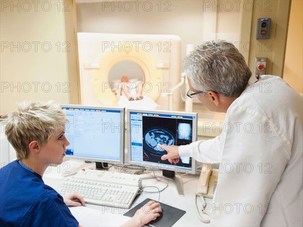 Doctor and nurse looking at CAT scan of patient's brain.