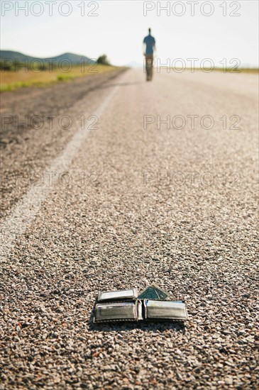 Man walking away leaving his wallet behind on empty road . Photo: Erik Isakson