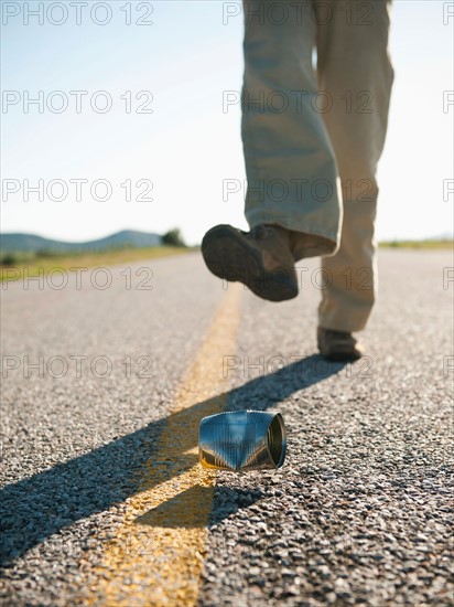 Man kicking tin can on otherwise empty road. Photo: Erik Isakson