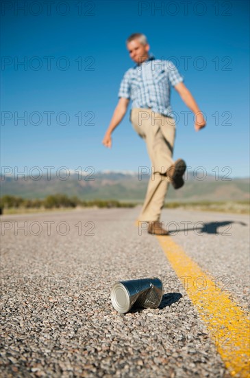 Man kicking tin can on otherwise empty road. Photo: Erik Isakson