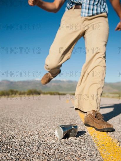 Man kicking tin can on otherwise empty road. Photo: Erik Isakson