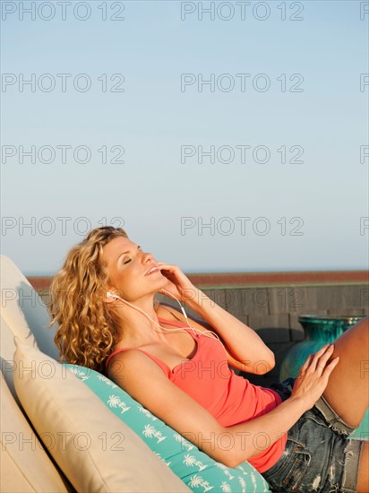 Young attractive listening to music on terrace.
