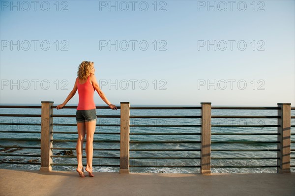 Young attractive woman contemplating seascape from terrace.