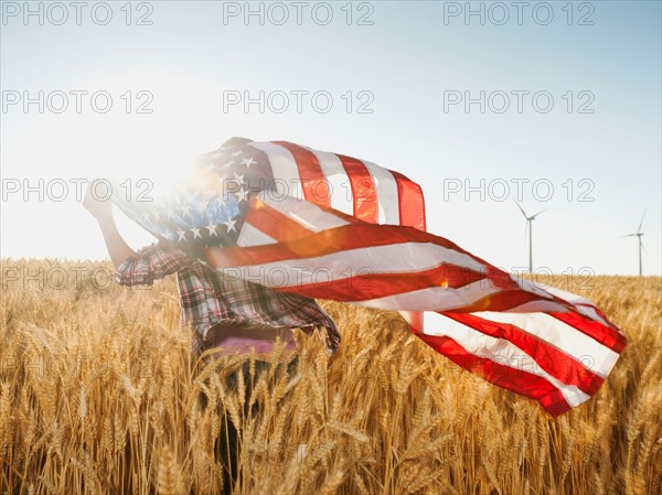 Girl (12-13) flying american flag in wheat field. Photo: Erik Isakson