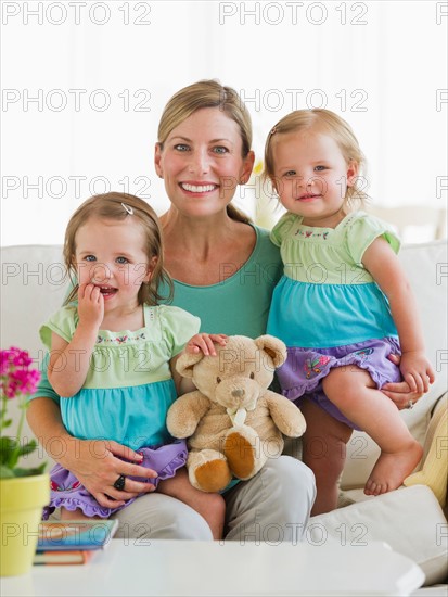 Portrait of mother with daughters (2-3) on sofa.