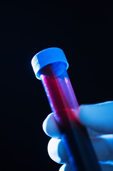 Studio shot of hand holding vial with blood.