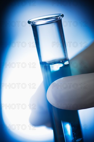 Studio shot of hand holding test tube with liquid.