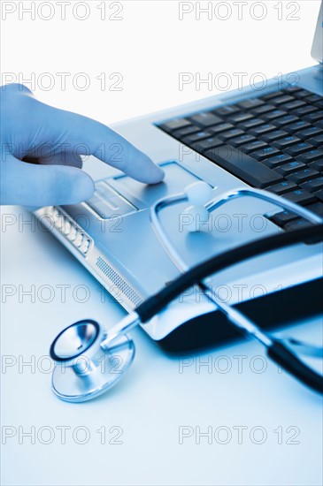 Studio shot of doctor's hand touching laptop.