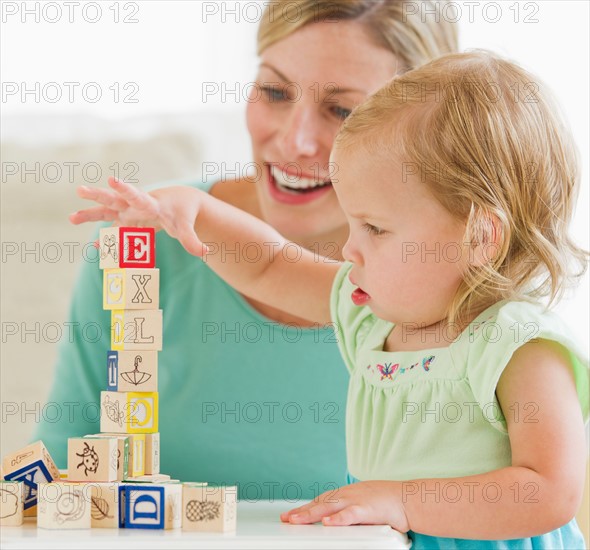 Mother and daughter (2-3) playing with letter blocks.