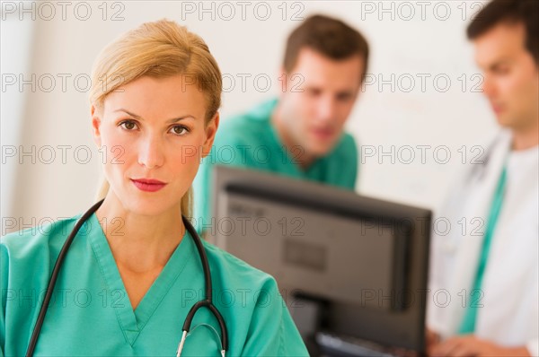 Portrait of female doctor in front of nurse's station.