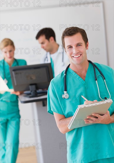 Portrait of male doctor in front of nurse's station.