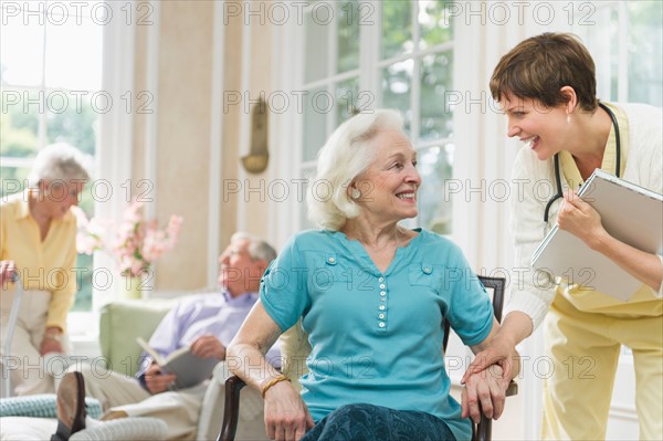 Senior woman and nurse talking outside nursing home.