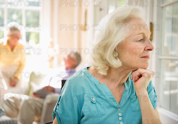 Senior woman looking through window in nursing home.