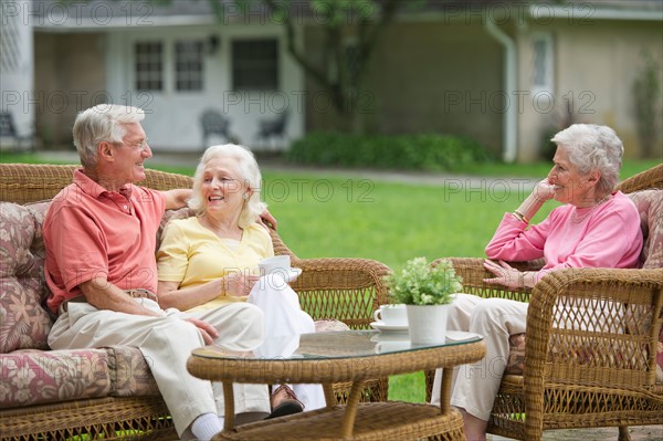 Seniors relaxing on outdoor sofa.