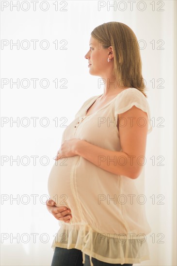 Pregnant woman looking through window.