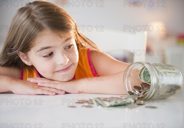 Girl ( 6-7) looking at savings in jar. Photo: Jamie Grill