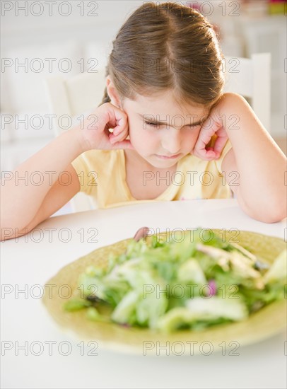 Upset Girl ( 6-7) sitting at table with salad meal. Photo: Jamie Grill