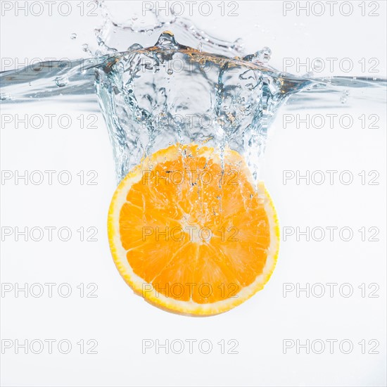 Orange splashing into water, studio shot. Photo : Daniel Grill