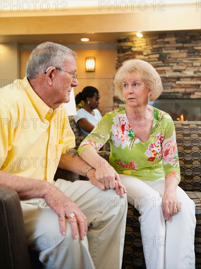 Senior people holding hands in hospital.