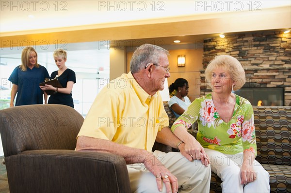 Senior people holding hands in hospital.