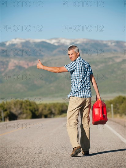 USA, Utah, Kanosh, Mid adult man carrying empty canister attempting to stop vehicles for help. Photo: Erik Isakson