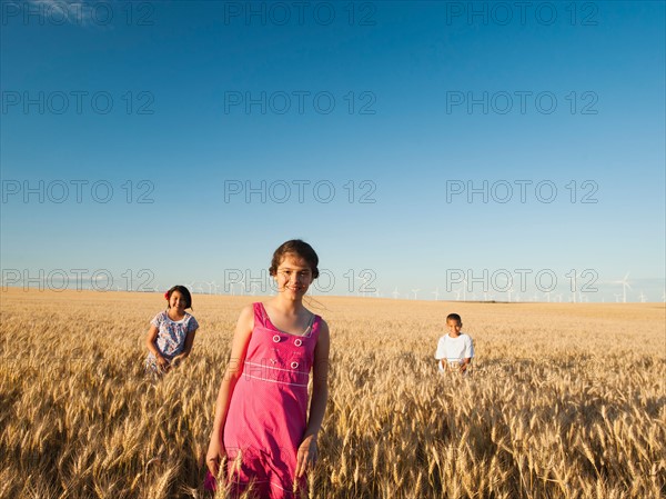 Girls (10-11, 12-13) and boy (8-9) standing in wheat field. Photo: Erik Isakson