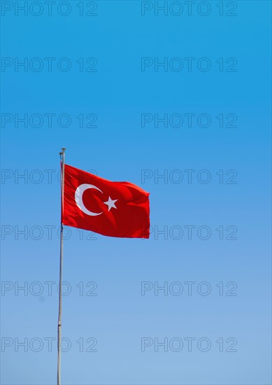 Turkey, Turkish flag against blue sky. Photo : Tetra Images