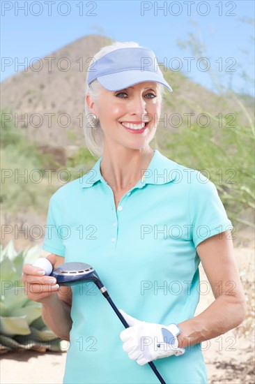 Portrait of mature woman holding golf club. Photo : db2stock