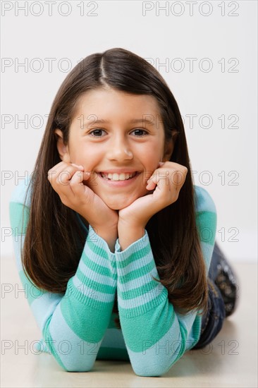 Studio portrait of girl (8-9) lying on floor. Photo : Rob Lewine