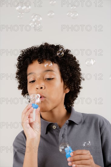 Studio portrait of boy (8-9) blowing bubbles. Photo : Rob Lewine