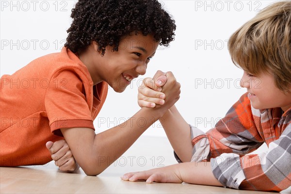 Studio shot of two boys (8-9) arm-wrestling. Photo : Rob Lewine
