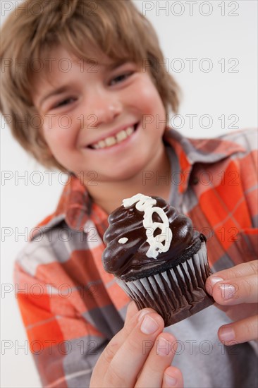 Studio portrait of boy (8-9) holding cake. Photo: Rob Lewine