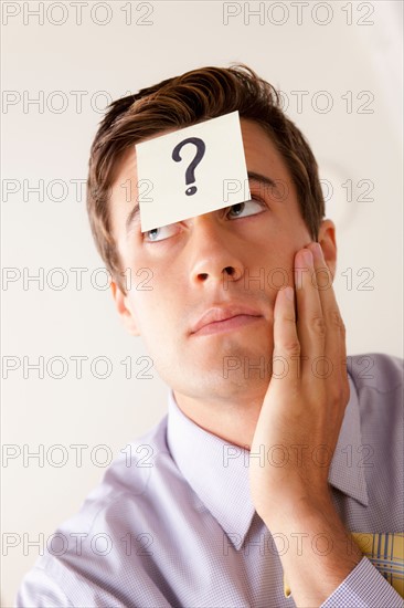 Portrait of businessman with adhesive note attached on forehead. Photo : Rob Lewine